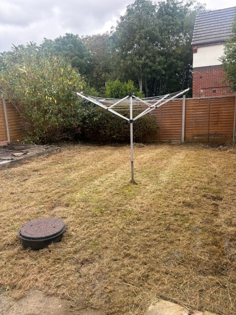 Overgrown residential garden with rotting decking and long grass before clearance — photo 2
