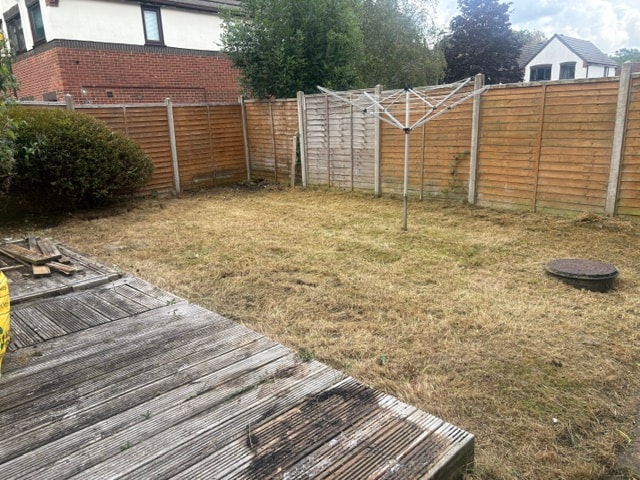 Overgrown residential garden with rotting decking and long grass before clearance — photo 3